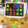 A wooden chalkboard display showing magnetic letters A-E, a-e, and numbers 1-4 plus sign.