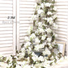 Artificial sakura flower garland with white blossoms and green leaves draped against a white slatted background