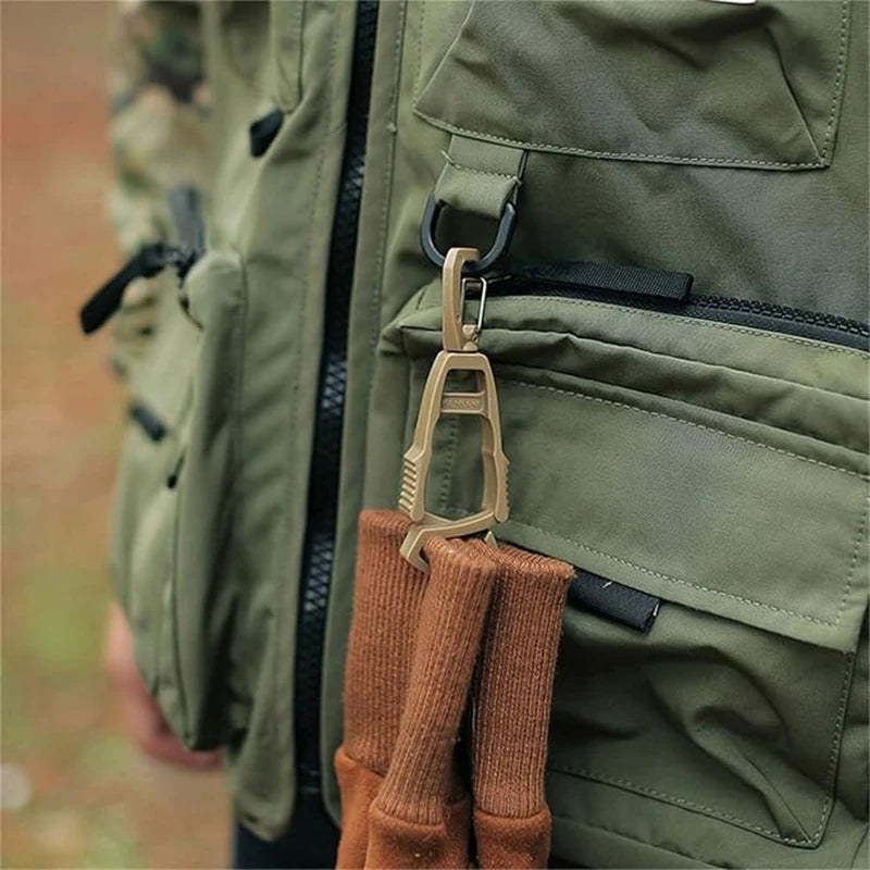 A close-up of a tan glove clip holder attached to a green military-style jacket pocket.