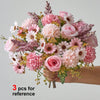 A bouquet of artificial silk flowers in shades of pink and cream, held by a hand.