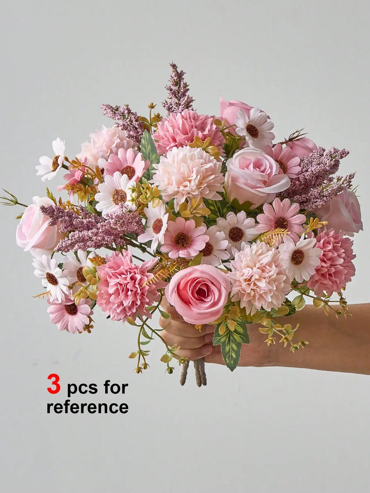 A bouquet of artificial silk flowers in shades of pink and cream, held by a hand.
