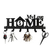 Black metal wall-mounted key holder with seven hooks featuring a house and dollar sign design