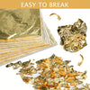A pile of shiny imitation gold leaf sheets and loose gold foil pieces for crafting.
