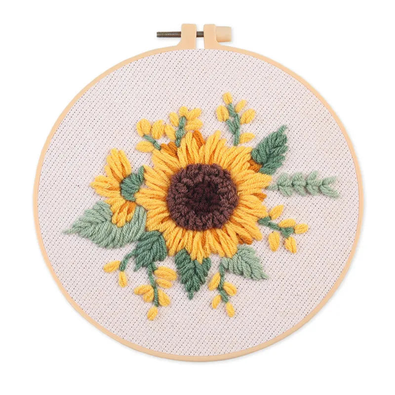 Punch needle embroidery kit featuring a sunflower design on a piece of cloth with tools.
