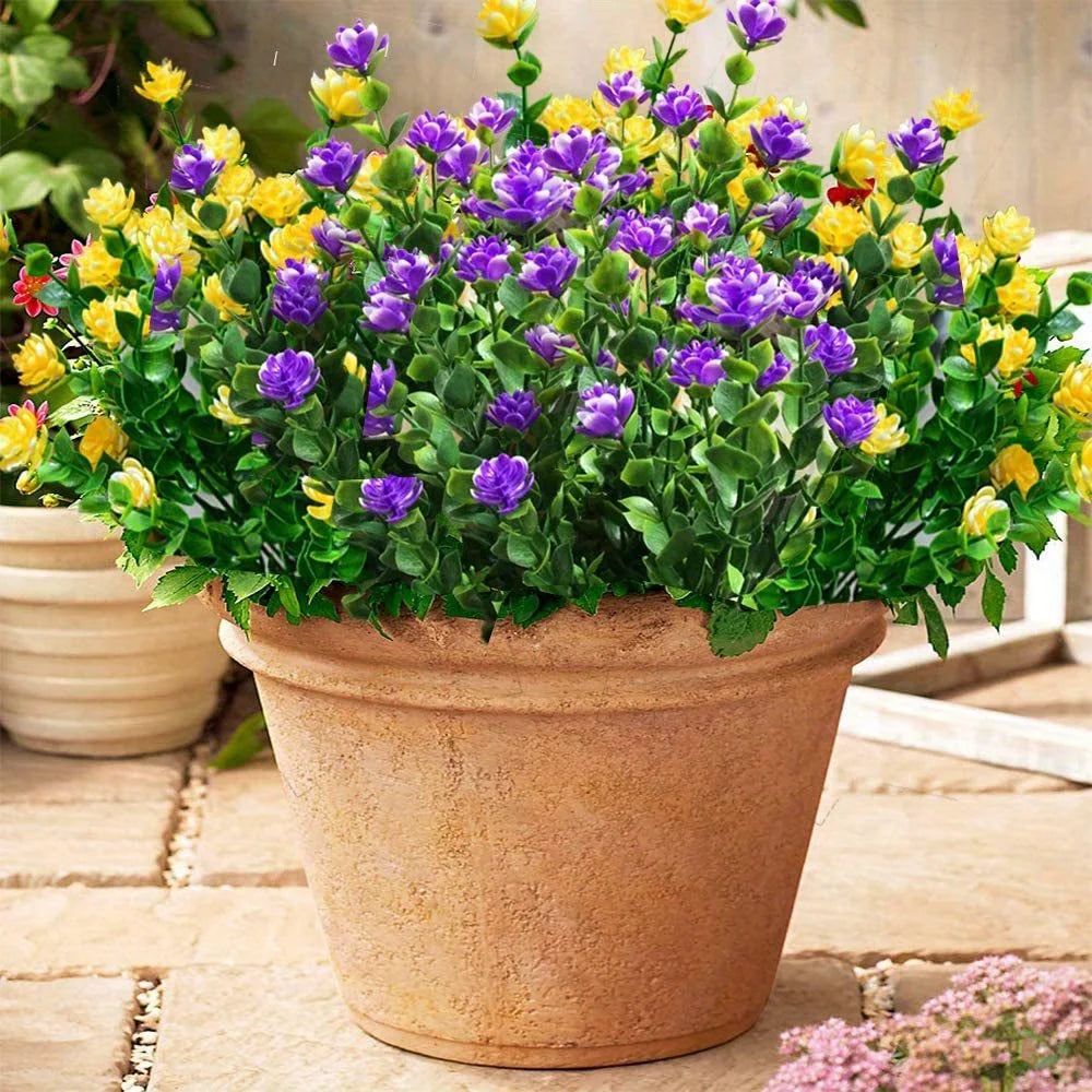 ترتيب زهور صناعية أرجوانية وصفراء في أصيص من التيراكوتا.