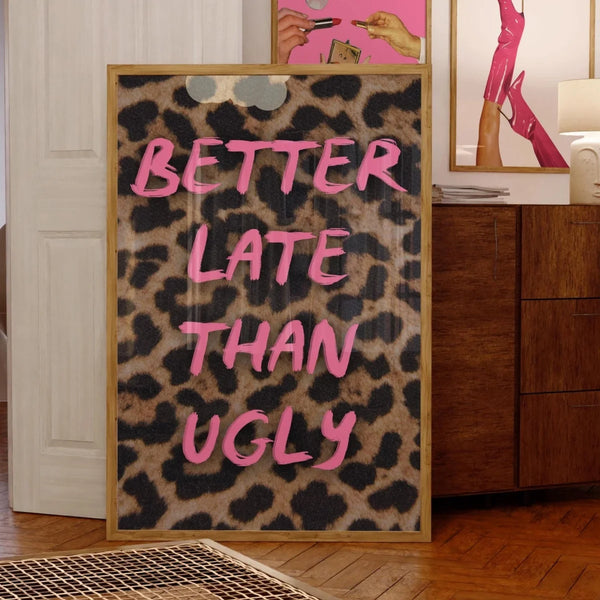 A framed canvas print featuring the text BETTER LATE THAN UGLY in bright pink lettering on a leopard print background.