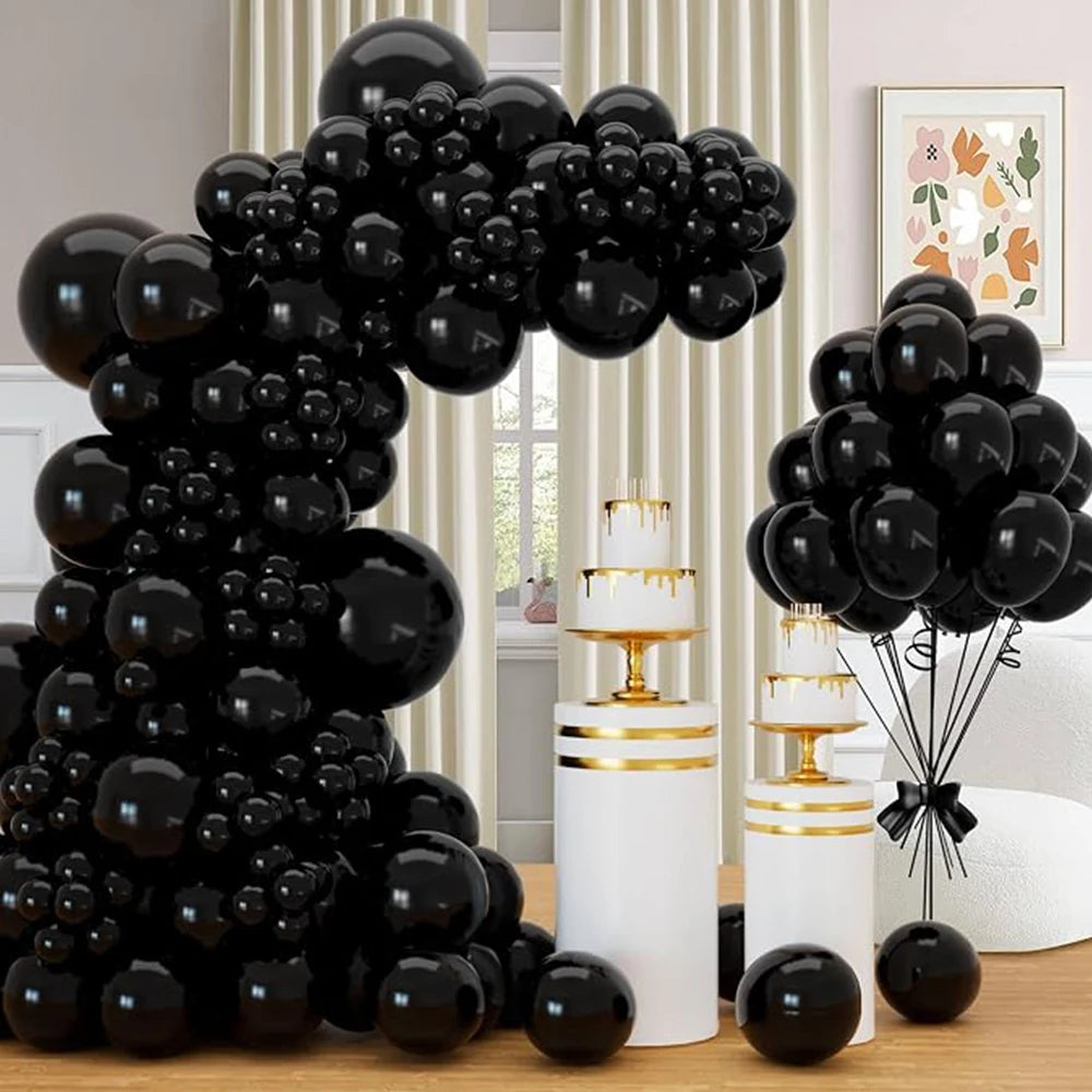 A large black balloon garland arch kit featuring various sizes of glossy black balloons displayed on a wooden surface.