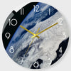 A round wall clock face showing a view of Earth from space with a golden hand pointing to the 12 o'clock position.