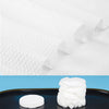 A stack of white compressed camping towels on a dark surface.