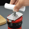 A hand is using a stainless steel multi-function bottle cap opener to open a glass jar.
