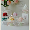 A bouquet of artisan tulips displayed alongside various soy wax candles in pink, yellow, and red hues.