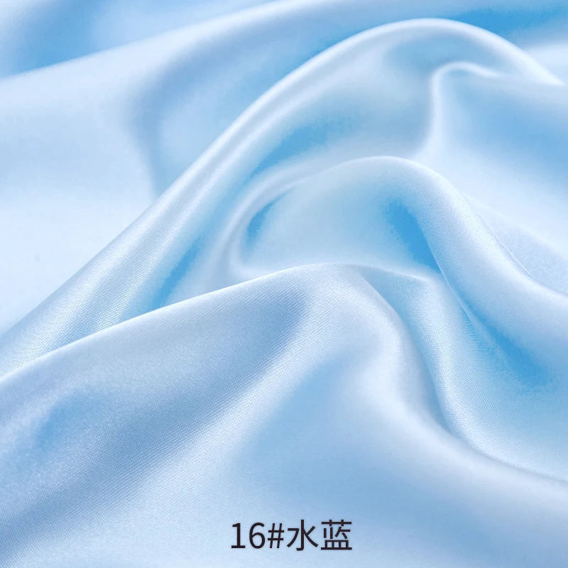 Close-up of light blue satin fabric draped and folded to show texture and sheen.