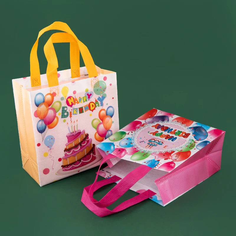 A set of reusable happy birthday gift bags in pink and white with yellow handles, featuring colorful balloons and a cake desi