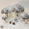 A display of mushroom-shaped disco ball decorations made of silver mosaic tiles.