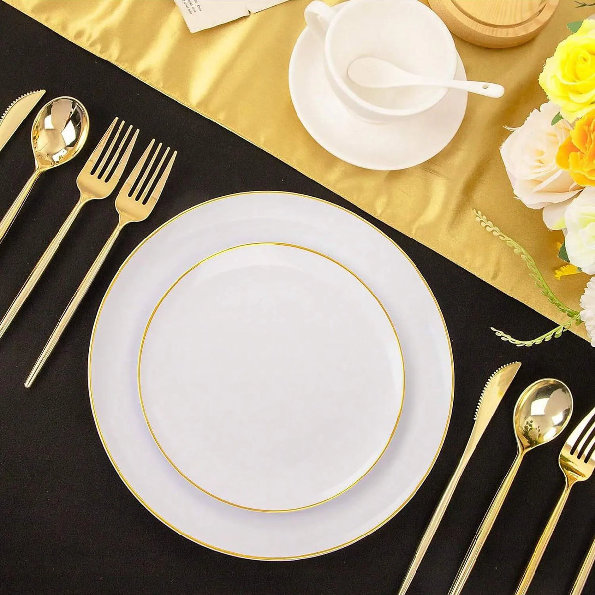 A set of gold rim plastic plates is displayed on a black surface with cutlery and a yellow napkin.