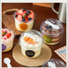 A collection of reusable pudding cups filled with layered desserts like fruit and cream, set on a wooden surface.