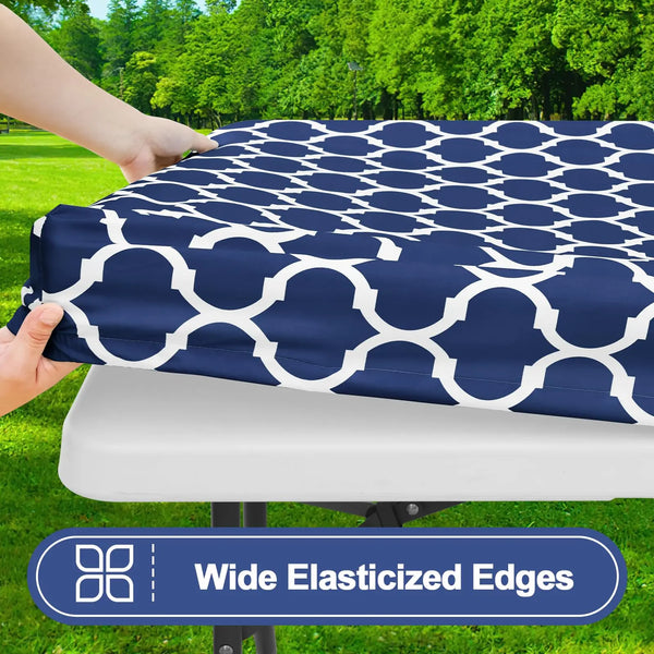 A navy blue waterproof elastic fitted tablecloth with a white geometric pattern is being held over a white table.