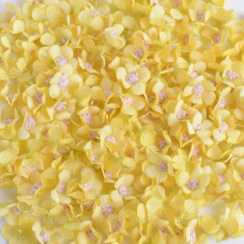 A pile of yellow silk artificial flower heads with pink accents for weddings and crafts