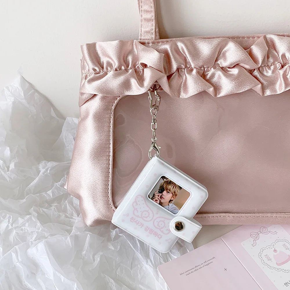 A pink satin photo album with a clear window displaying a small white snap button photo holder.