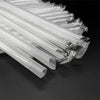 A close-up view of clear disposable plastic straws bundled together on a dark surface.