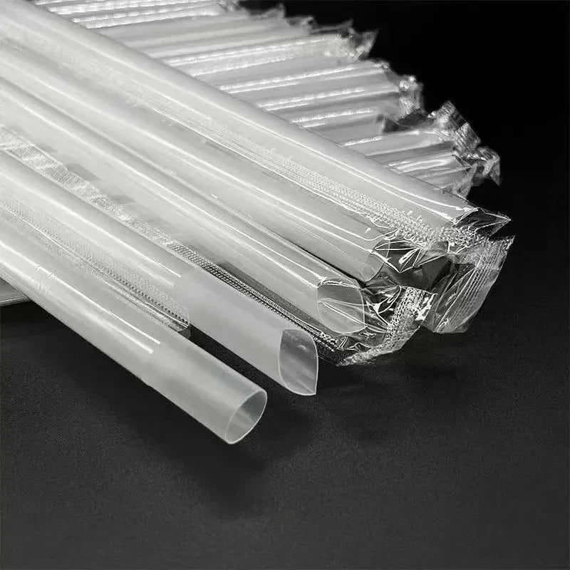 A close-up view of clear disposable plastic straws bundled together on a dark surface.