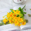 A bouquet of bright yellow artificial daisy flowers with green leaves displayed on an open book.