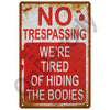 A vintage metal sign with red and white text warning against trespassing and hiding bodies.