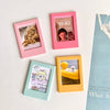 Four pink and yellow magnetic photo frames displaying different images and times on a white surface.