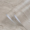 Roll of self-adhesive PVC wallpaper film with a wood grain texture shown rolled up on a wooden surface.