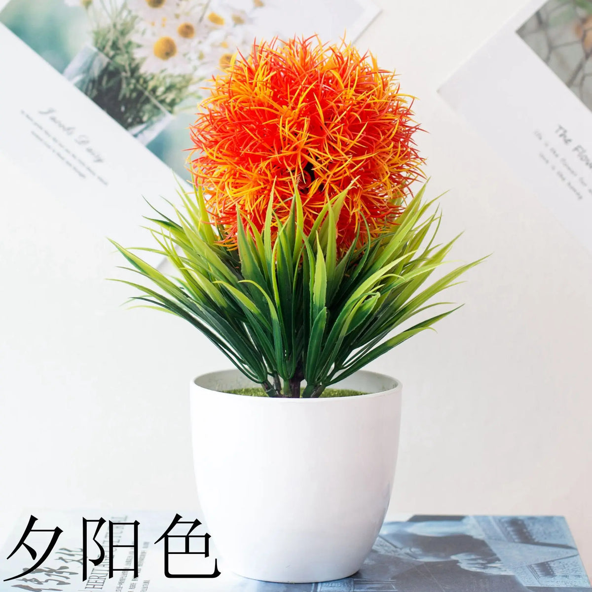Un arbre bonsai artificiel orange et rouge vif dans un pot blanc, sur fond clair.