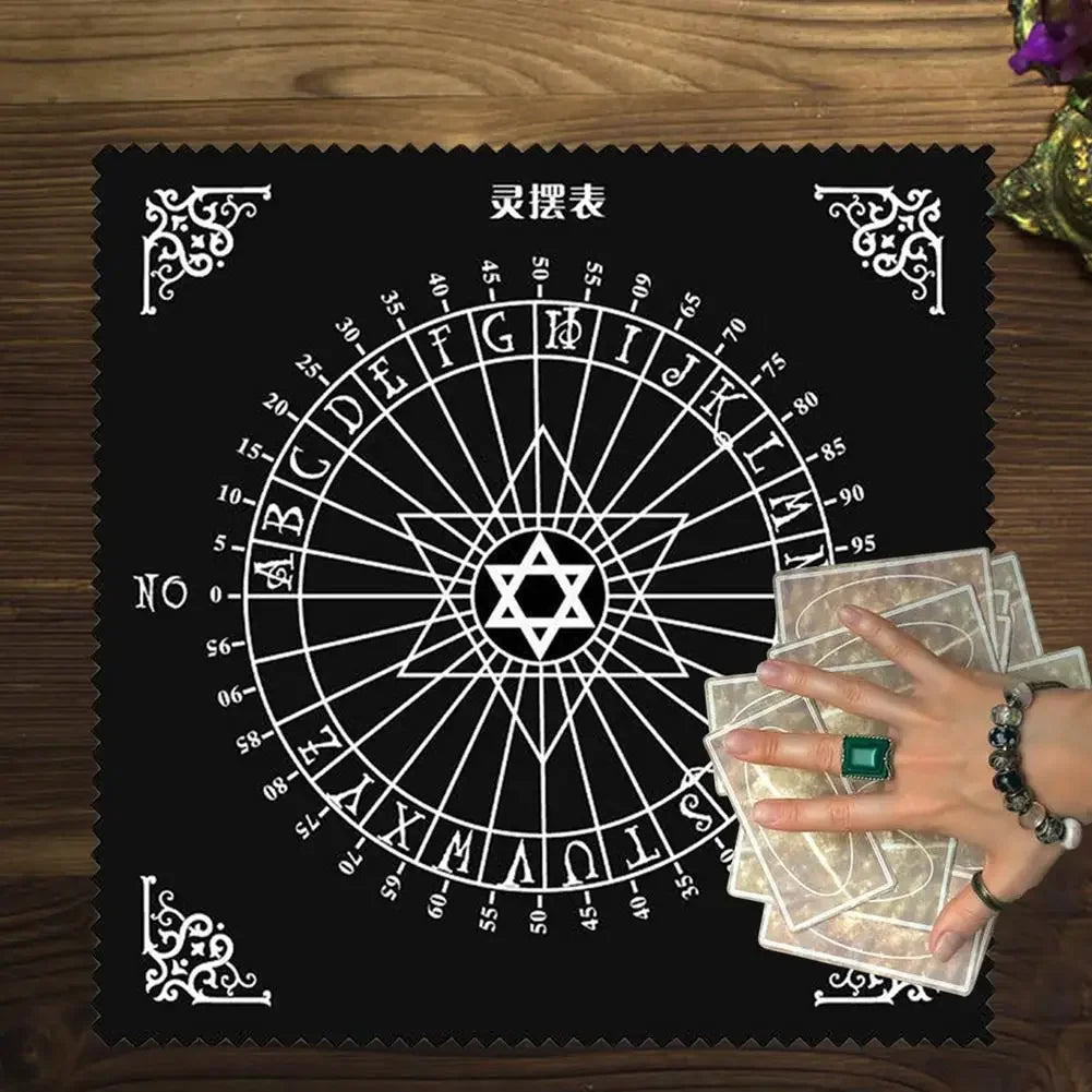 A black cloth featuring a pentagram tarot wheel design with letters and numbers, displayed on a wooden surface.
