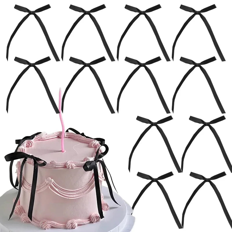 A set of twenty black bowknot ribbon cake toppers is displayed next to a pink cake.