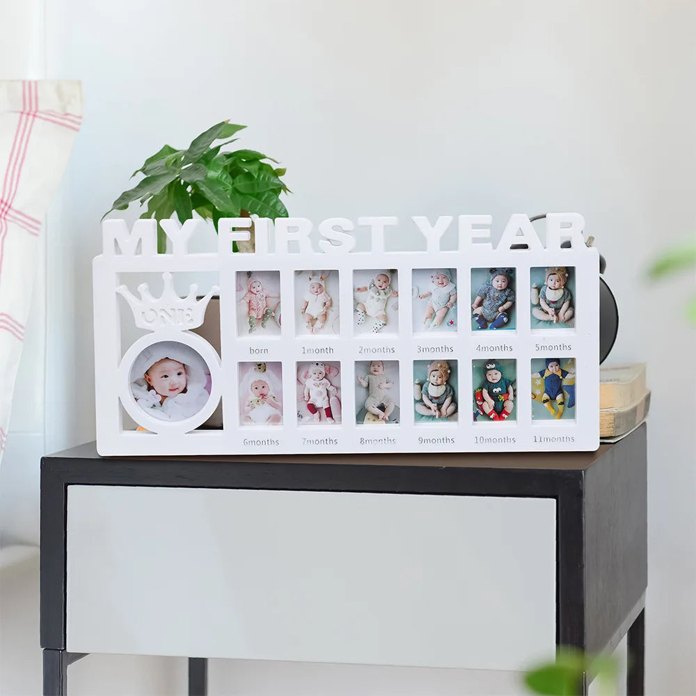 A white photo frame display showing monthly growth photos for a baby's first year, including a crown motif.