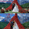 A couple stands in a dramatic red rose petal mountain backdrop for an outdoor wedding ceremony.