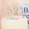 A white cake decorated with gold number candles spelling 520 and colorful candies for a birthday celebration.