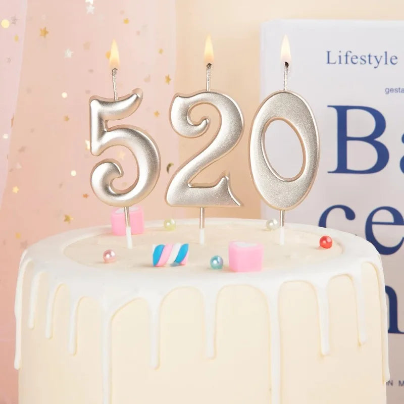 A white cake decorated with gold number candles spelling 520 and colorful candies.