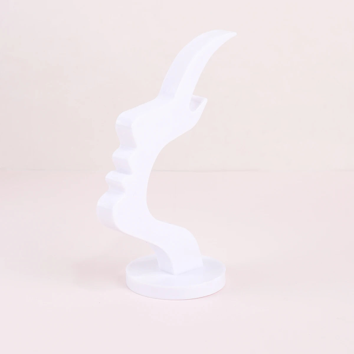 A white minimalist side face glasses holder displayed on a light pink surface.