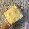 A hand holds a large, pale yellow cheese cube stress ball with visible dimples.