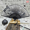 An elegant vintage Chinese folding hand fan displayed on a wooden stand with bamboo sticks.