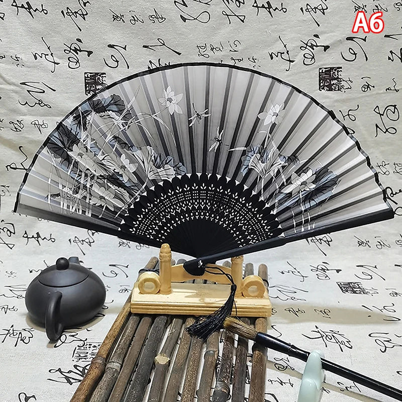 An elegant vintage Chinese folding hand fan displayed on a wooden stand with bamboo sticks.