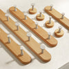 A wooden wall hook rack with four cylindrical hooks made of solid beech wood.