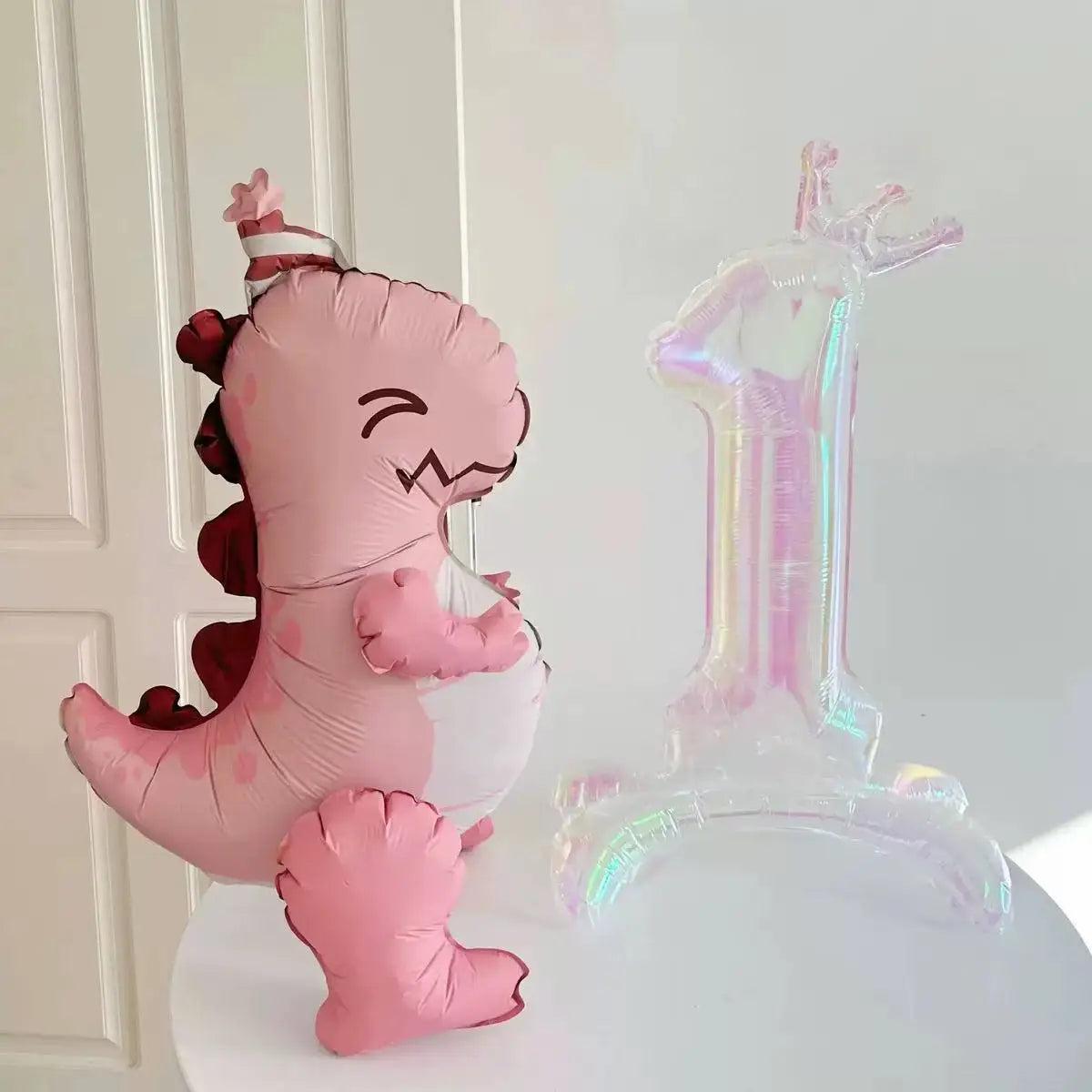 A pink dinosaur shaped balloon decoration and a clear number one balloon decoration.