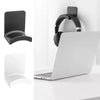 A black adhesive headphone stand mounted on a white desk next to a silver laptop.