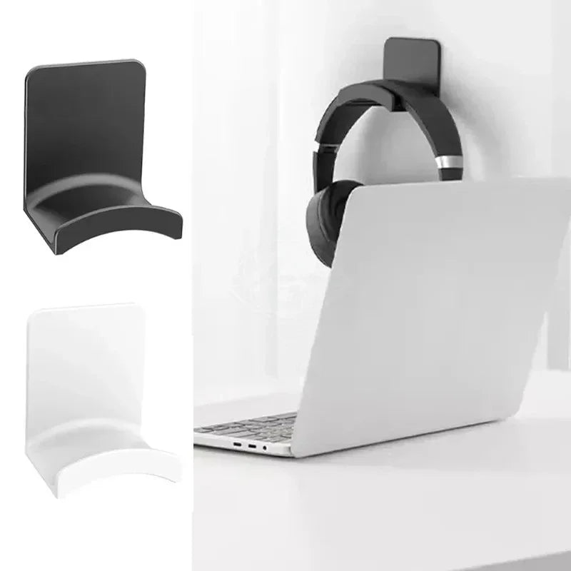 A black adhesive headphone stand mounted on a white desk next to a silver laptop.
