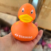 An orange rubber duck bath toy with a yellow beak and the STAWAG logo is held in a hand.