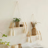 Macrame wood floating wall shelf with hanging rope displaying dried flowers and natural fibers.