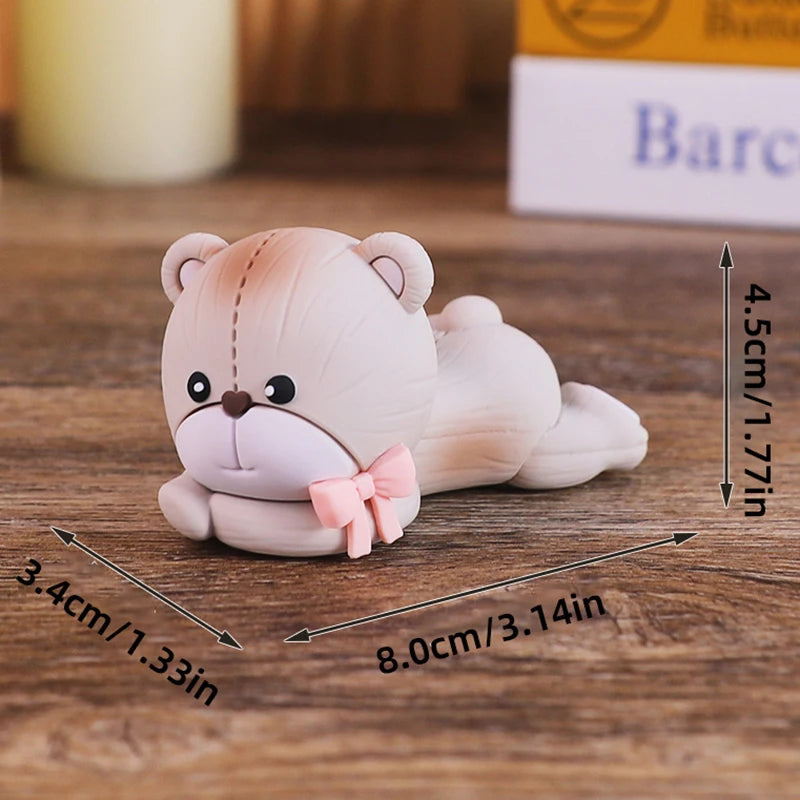 A light pink baby block cake topper shaped like a teddy bear with a bow, shown on a wooden surface.