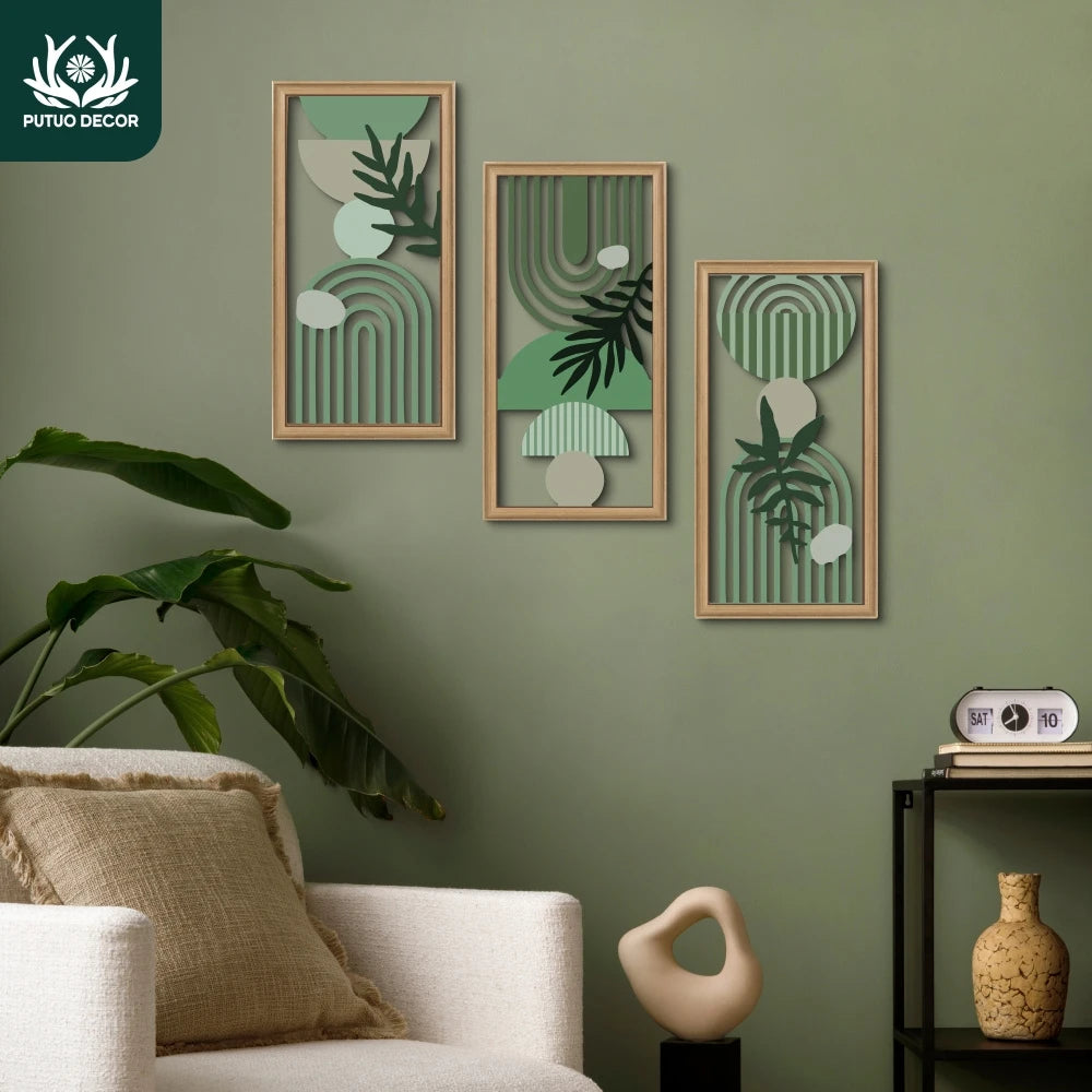 A set of three framed wall art pieces featuring botanical illustrations in muted green and beige tones on a sage green wall.