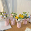 A collection of handmade floral bouquets featuring purple, white, yellow, and blue flowers in pink paper wrapping.