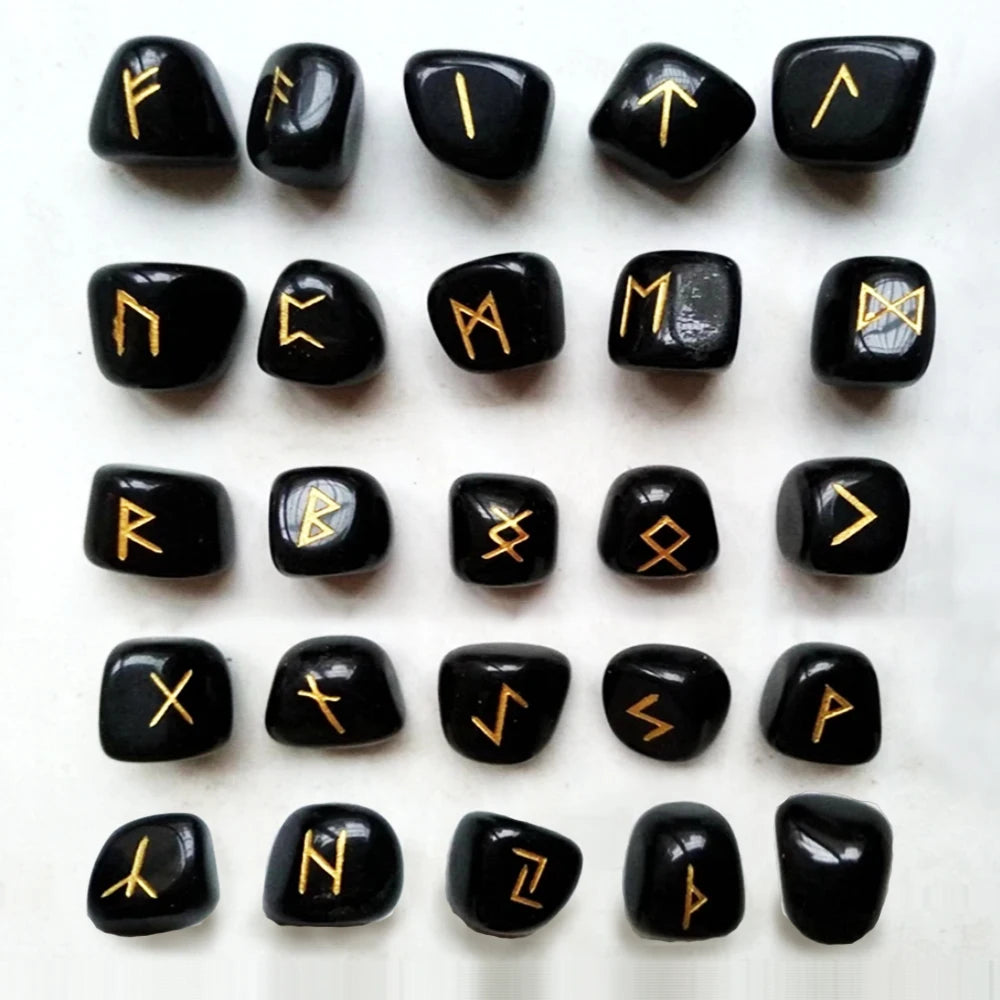 Una colección de piedras rúnicas de cristal natural en negro y oro dispuestas en una cuadrícula.
